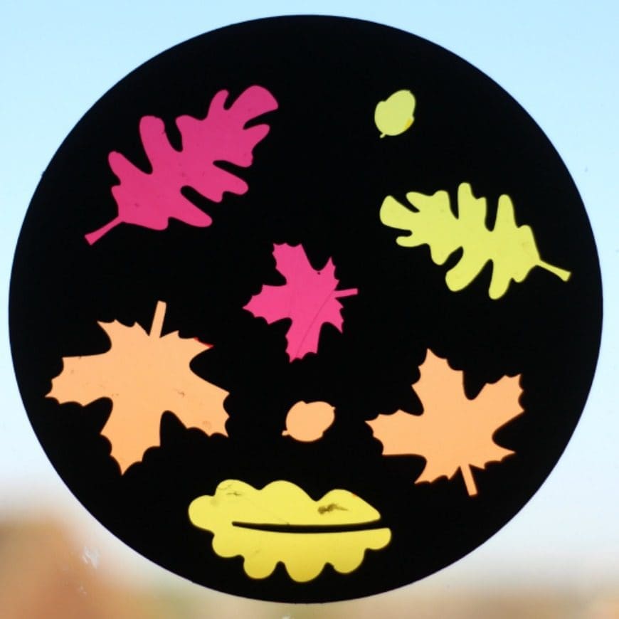 Autumn sun catcher. Make a beautiful cellophane sun catcher to celebrate fall. The black background really makes the autumnal colours pop. This is a super fun DIY craft activity for kids.