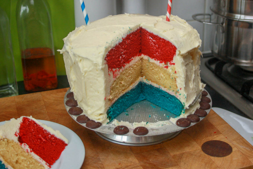 Red, white and blue layer cake with a white exterior and tiny union jack bunting hung on straws to celebrate the queens Jubilee 