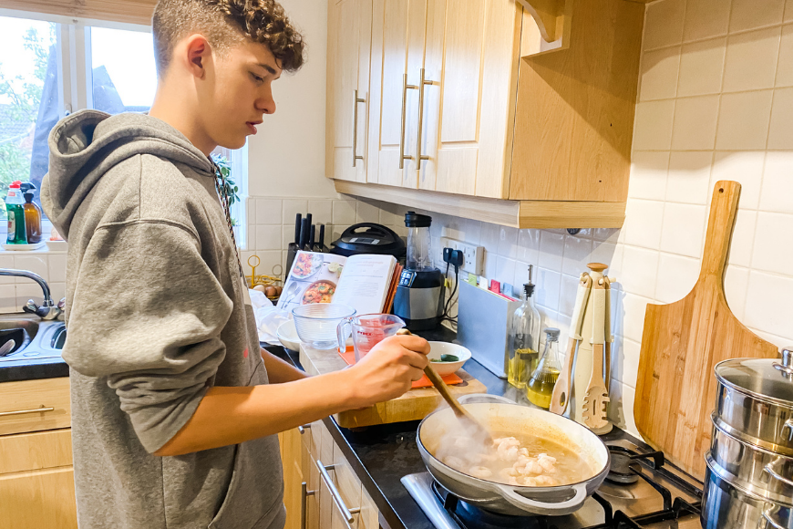 Teen in the kitchen cooking a King Prawn and Spicy Maple Curry 