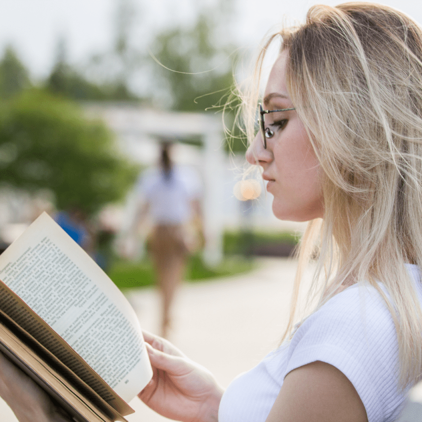 Woman with blond hair  and glasses reading a book